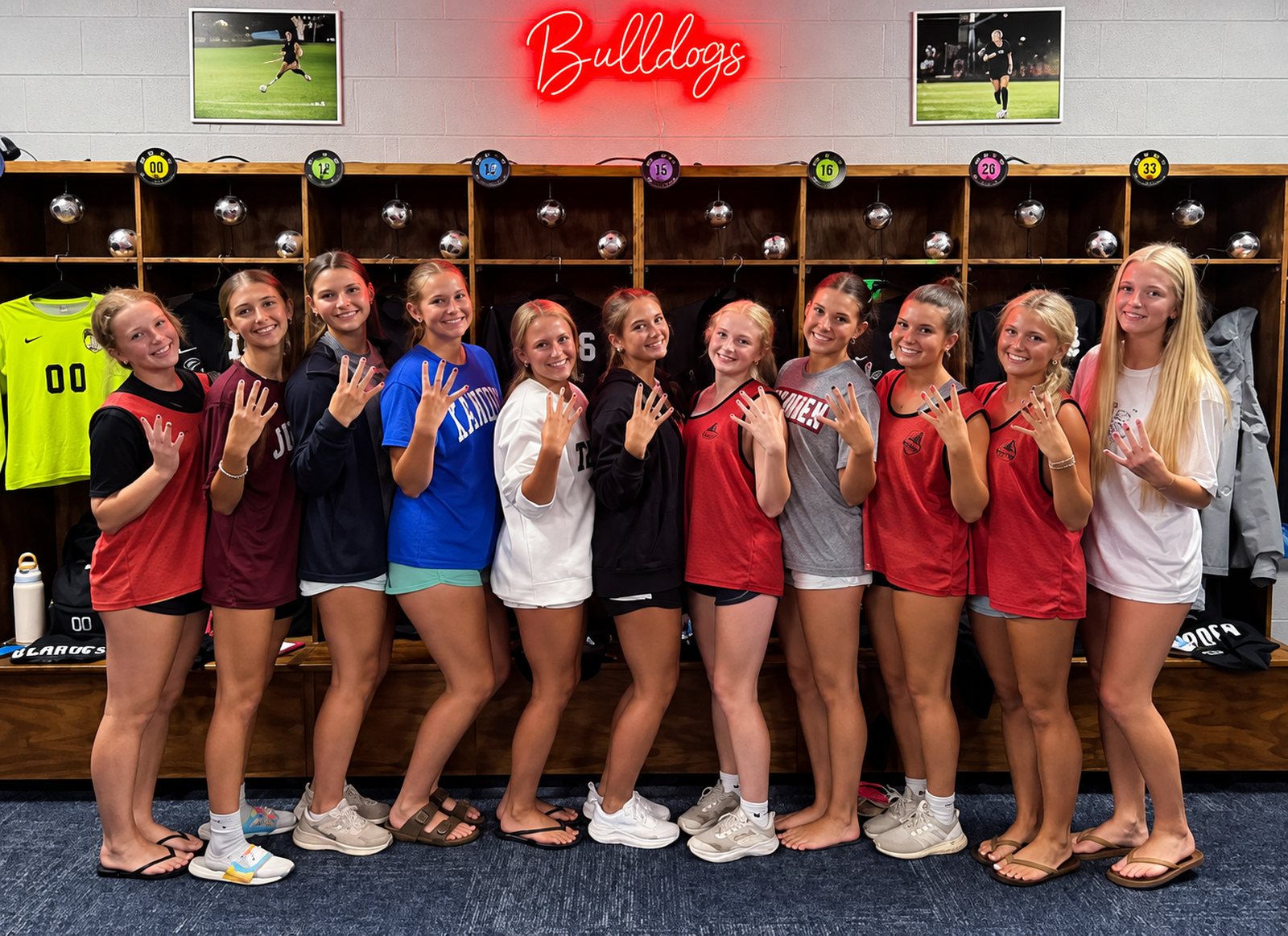 Eleven Bearden players line up beneath a red Bulldogs neon sign, each holding up four fingers.
