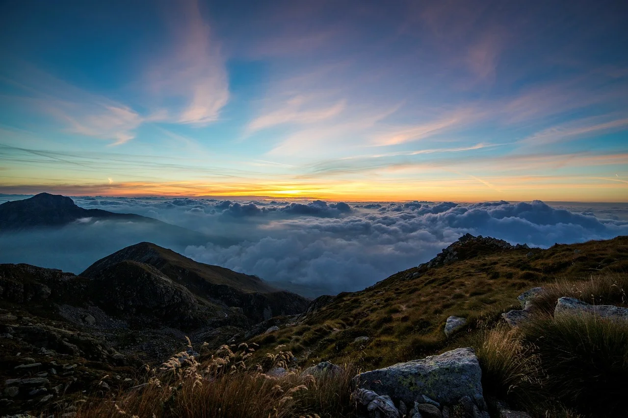 Sunrise opening a wider view above a mountain ridge and clouds