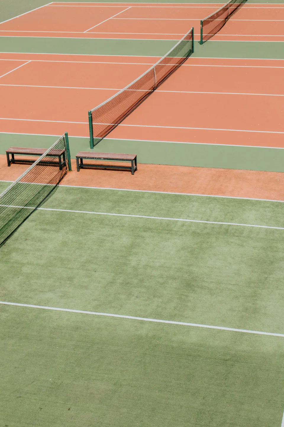 Green and terracotta tennis courts crossed by a diagonal net